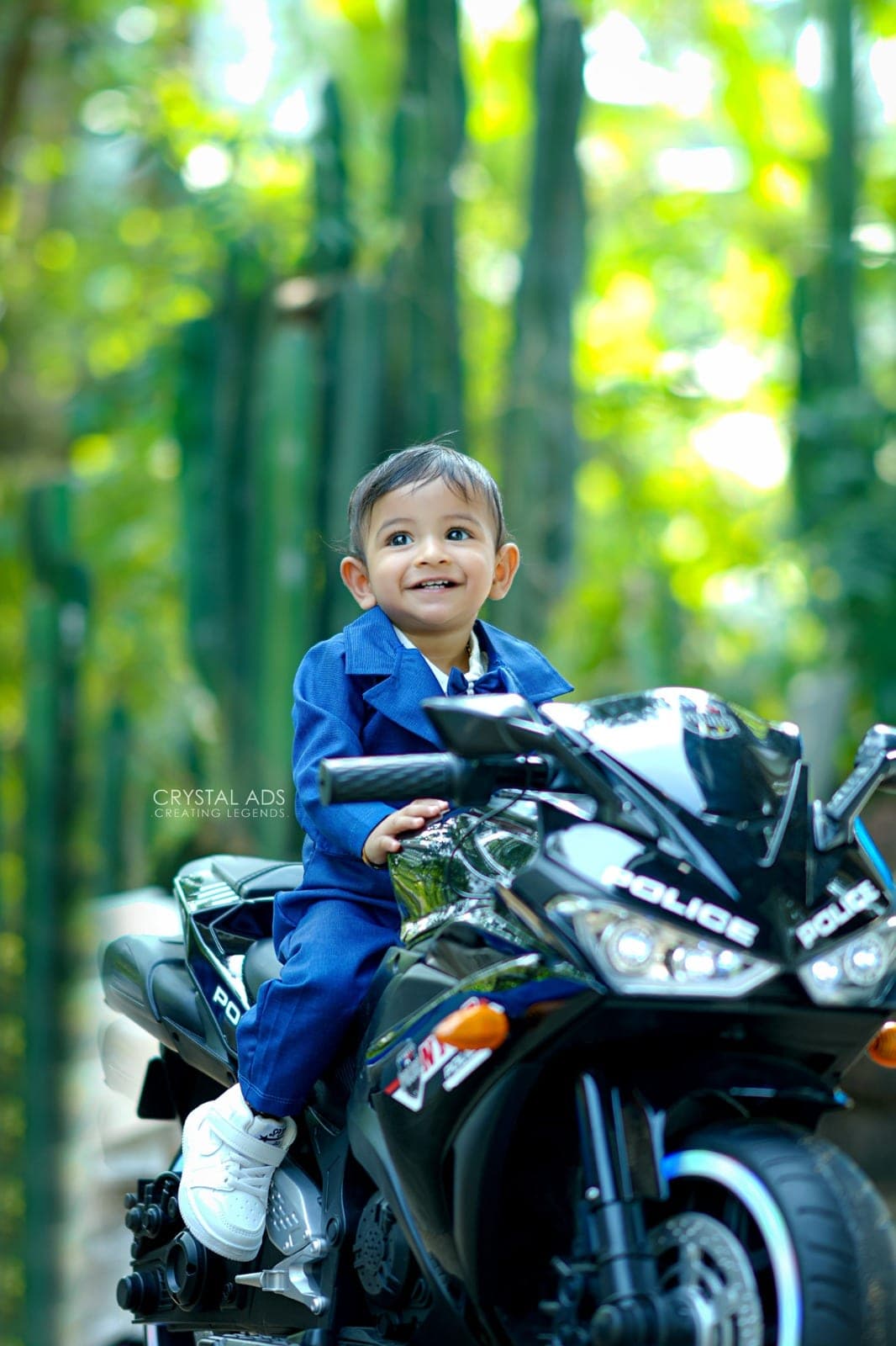 Baby boy in a blue suit sitting on a toy motorbike