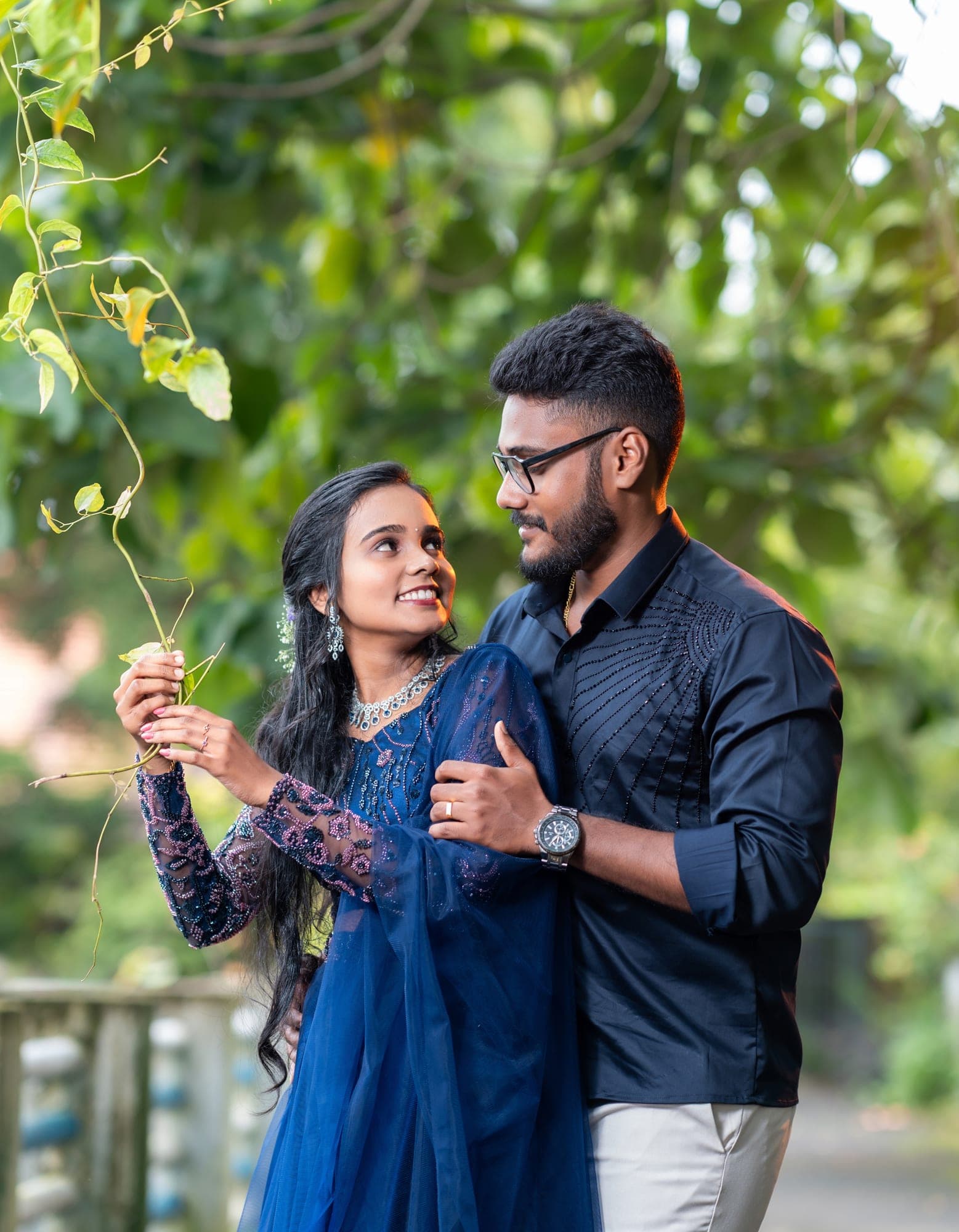 Engaged couple smiling at each other under a hanging vine