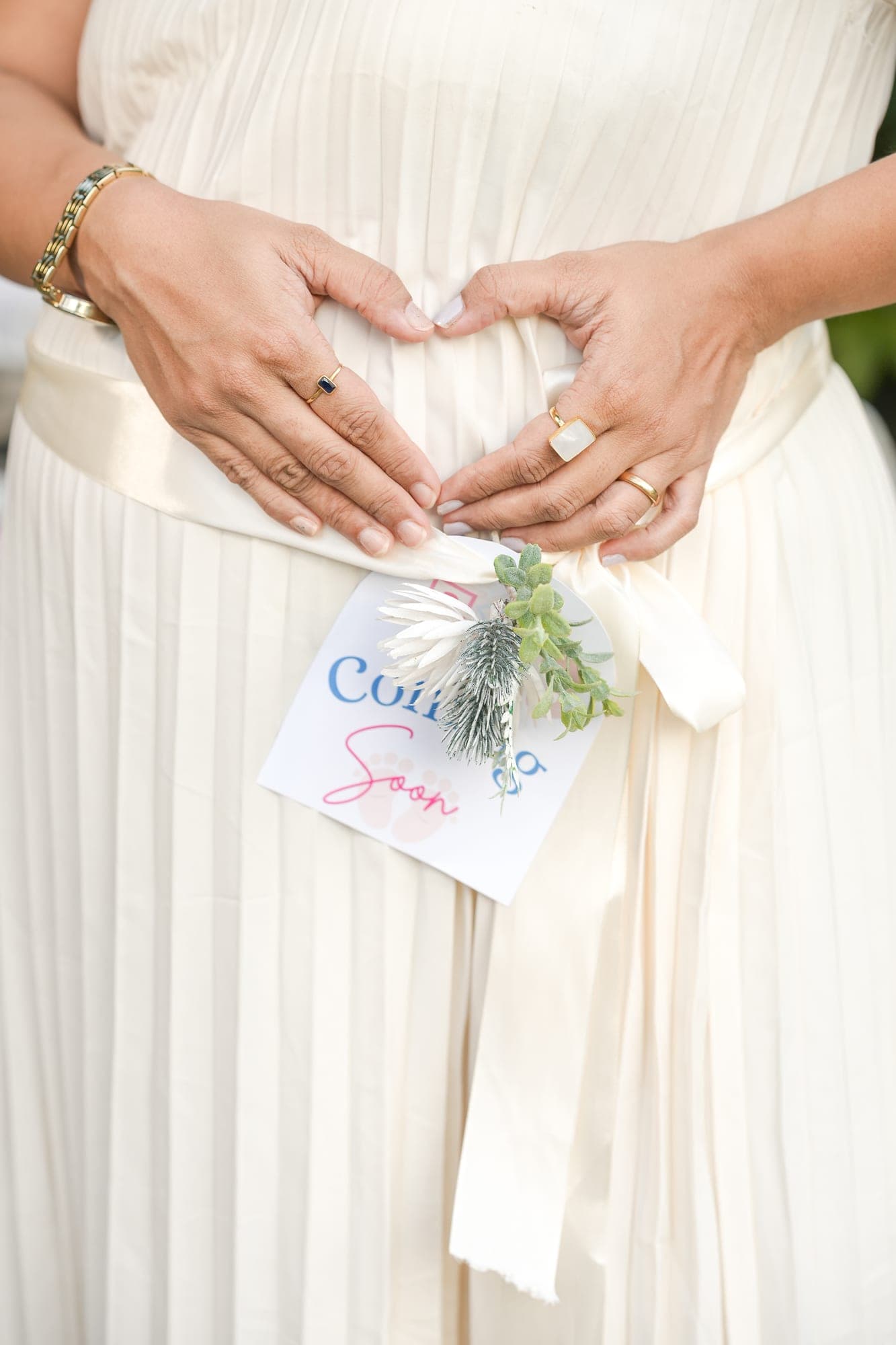 Close-up of expecting mother's hands forming a heart over her belly
