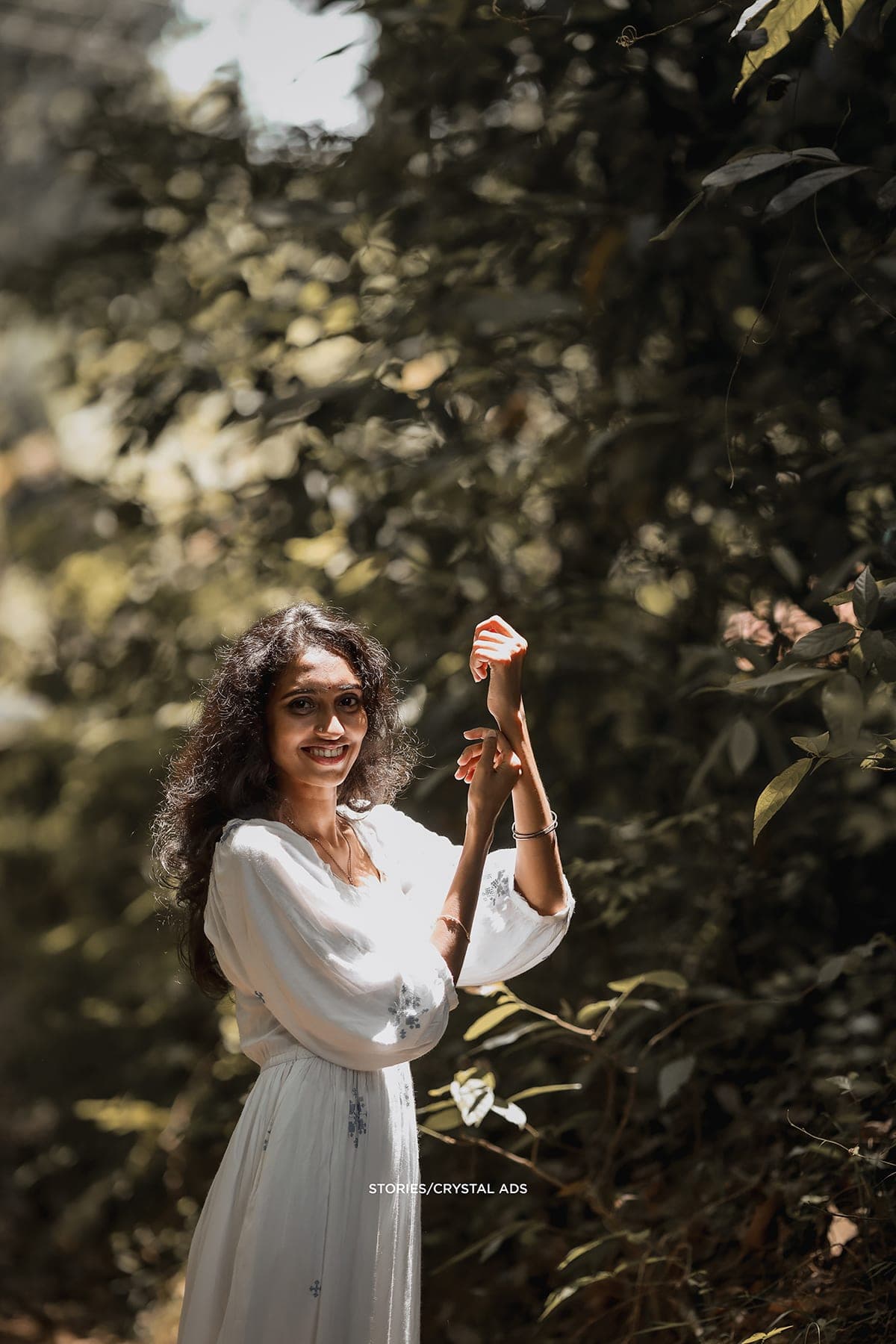 She reaches up into the leaves, smiling