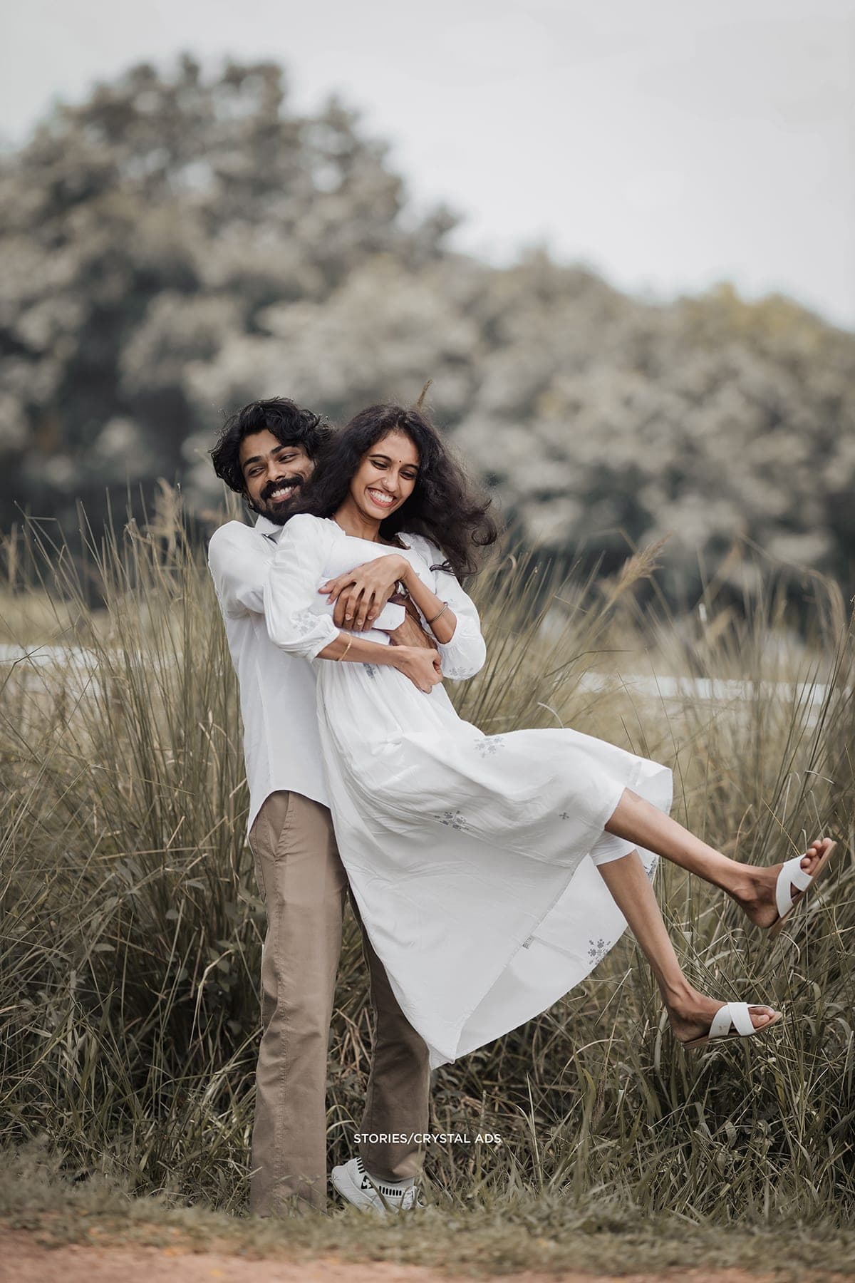 He lifts her playfully in the tall grass