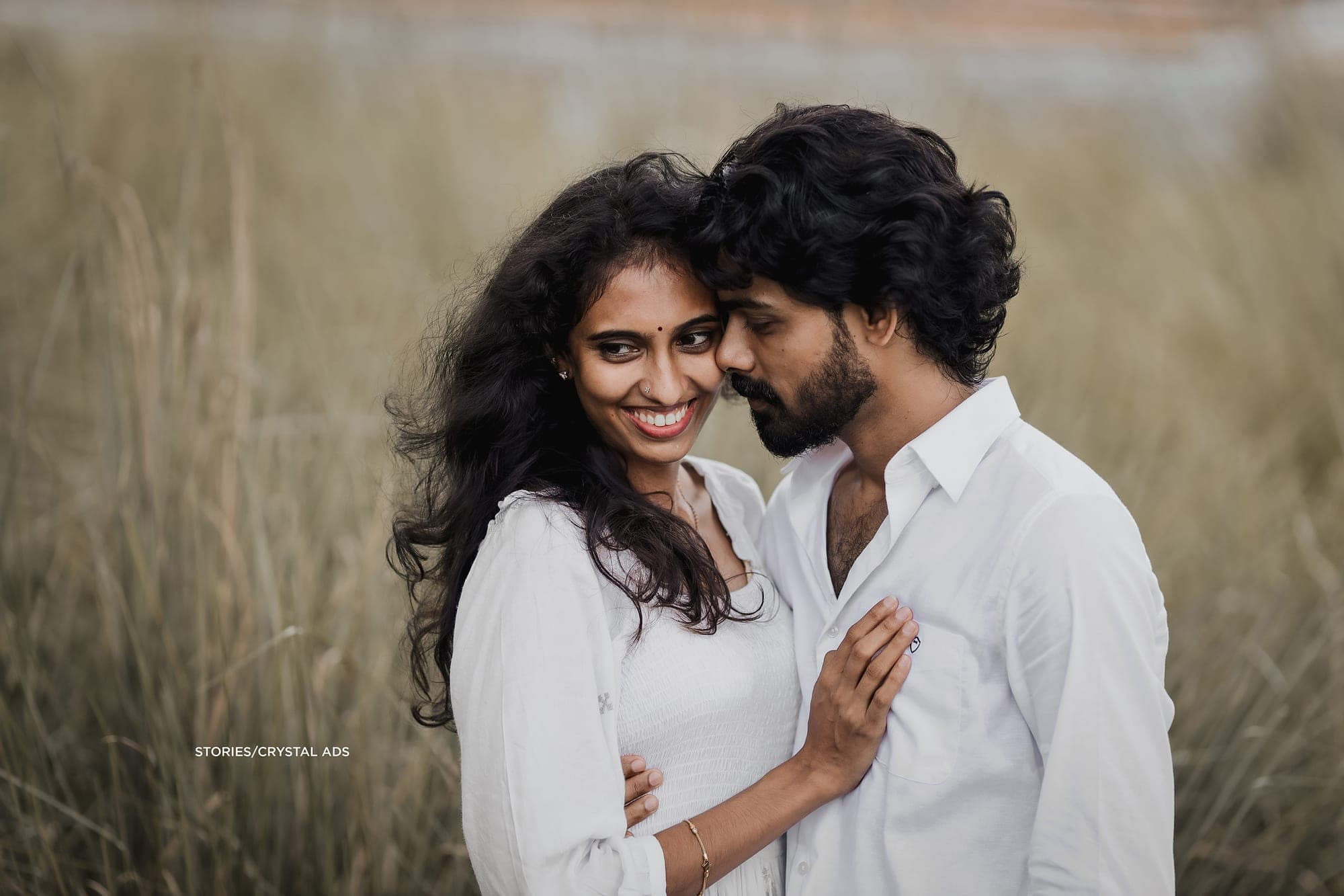 Close portrait in tall grass, she laughs as he leans in
