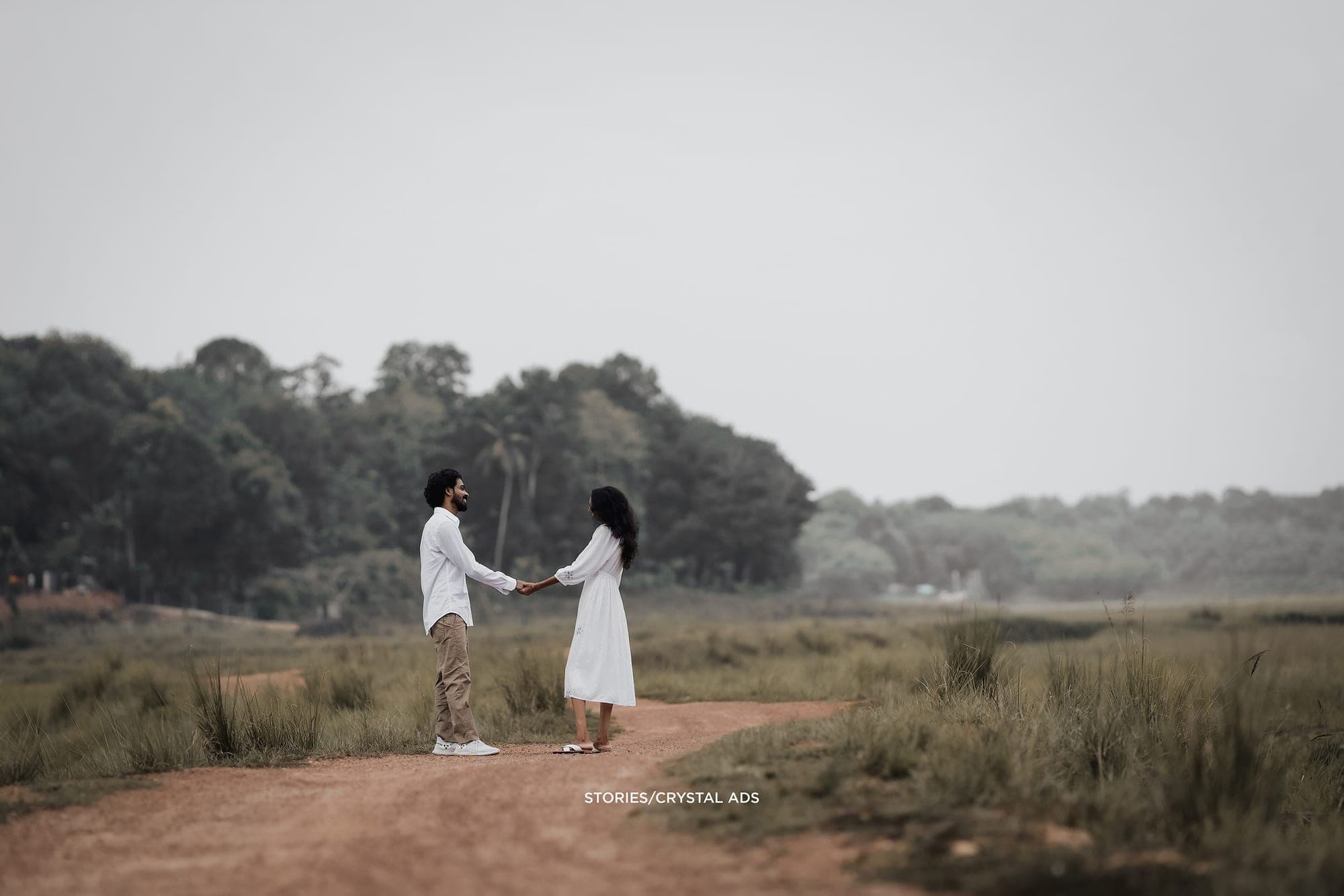 Wide view of the couple holding hands on a dirt path