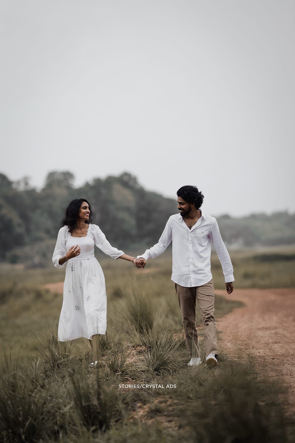 Couple walking hand in hand along a dirt path
