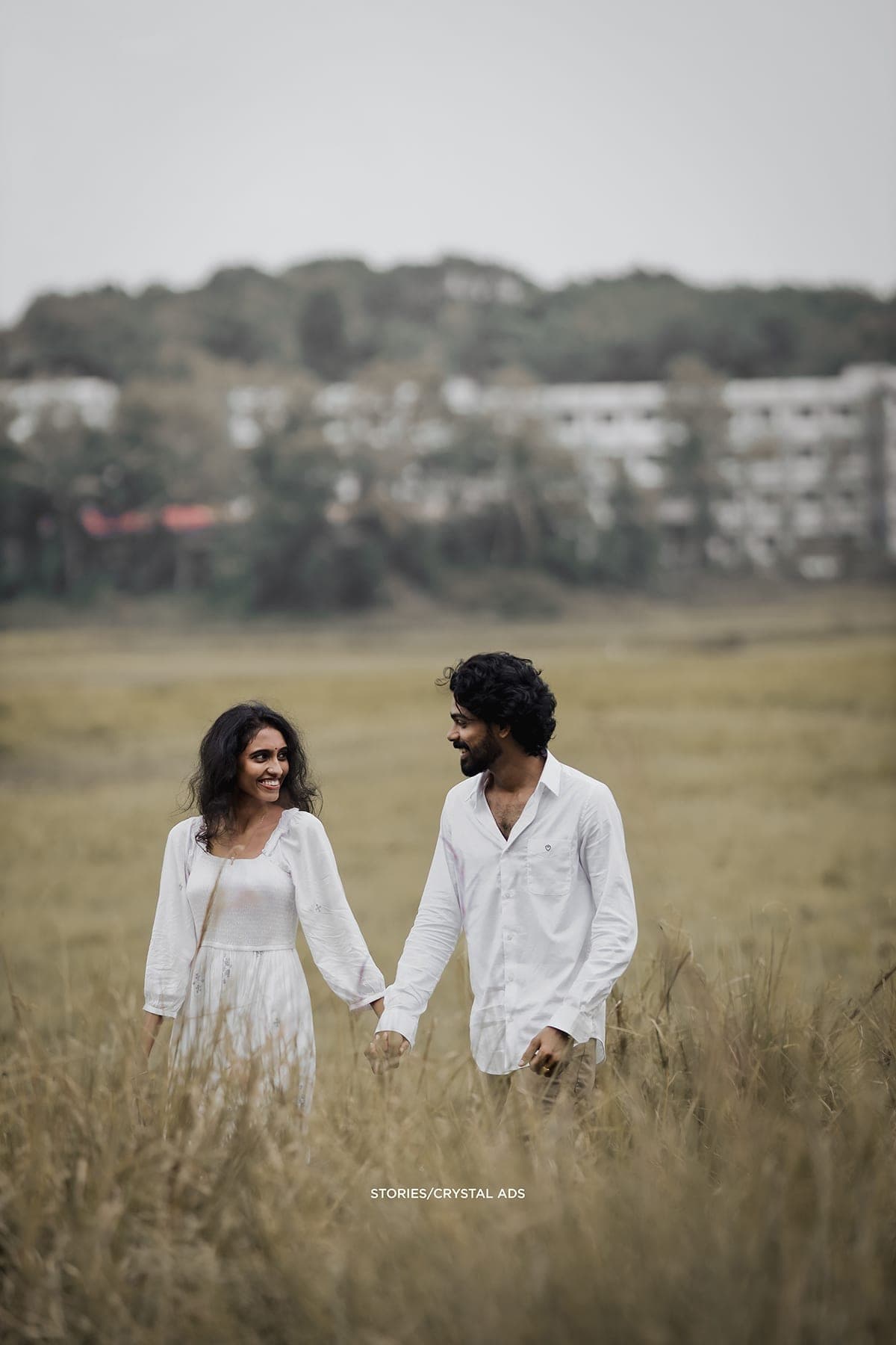 Couple walking through a meadow, smiling at each other