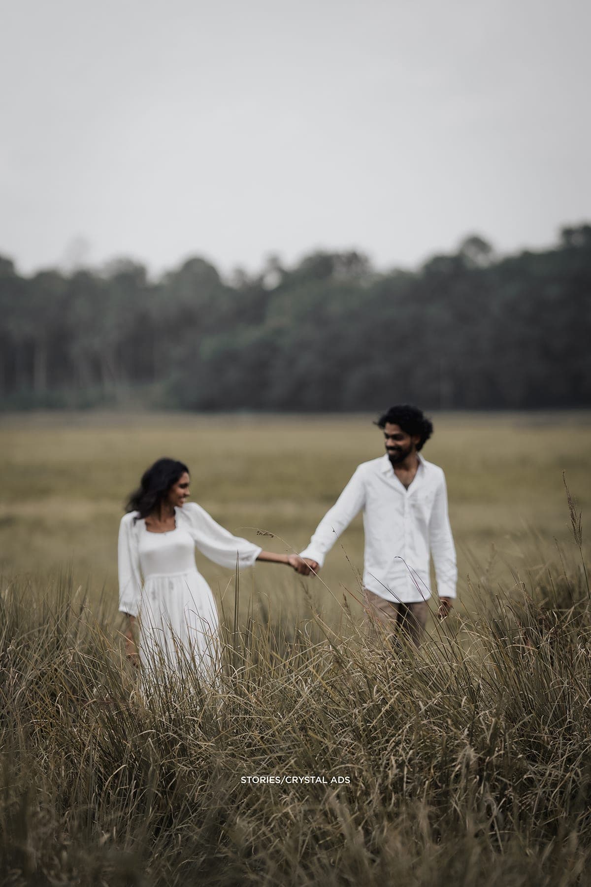 Couple holding hands at arm's length in an open field