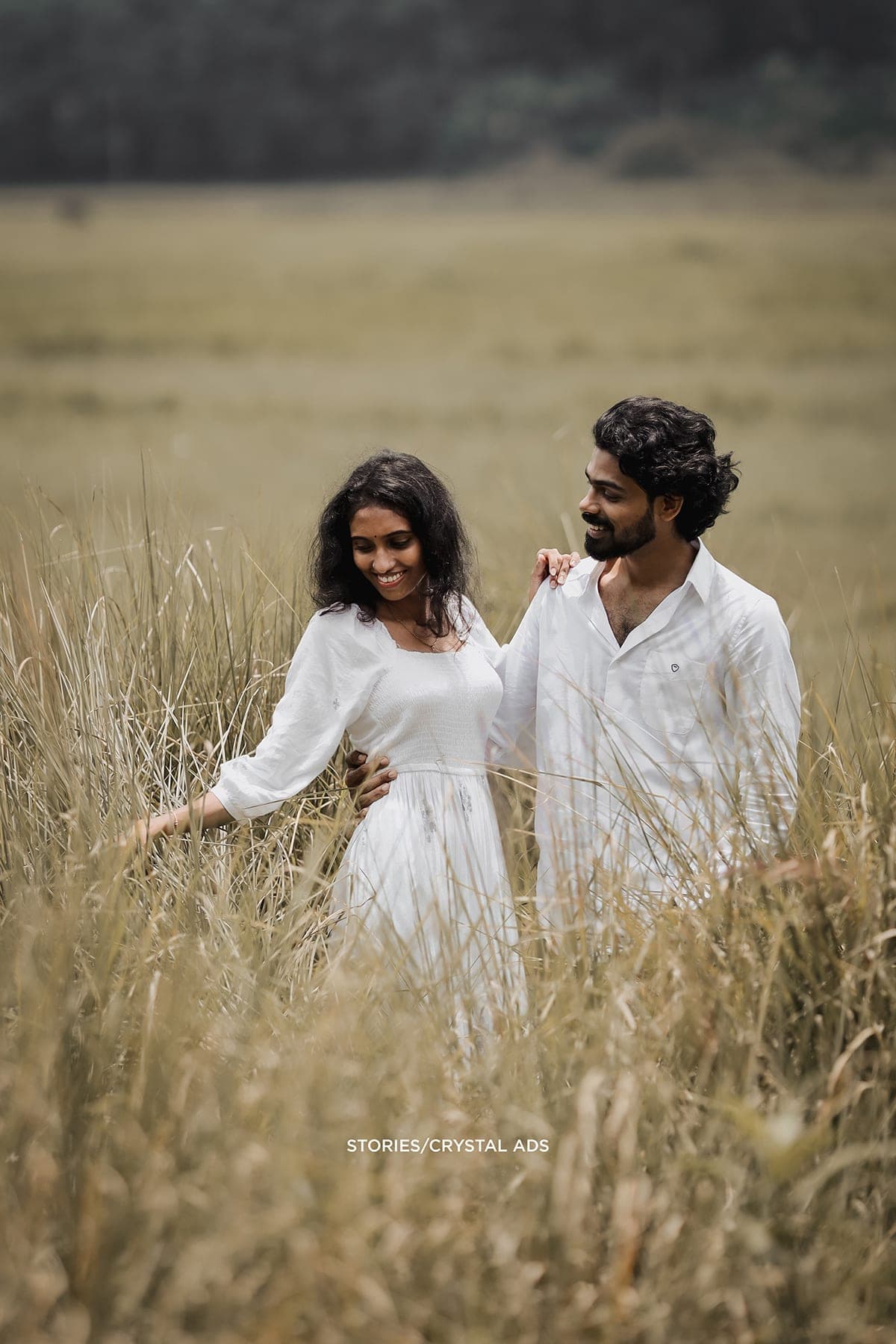Couple walking through tall grass, laughing