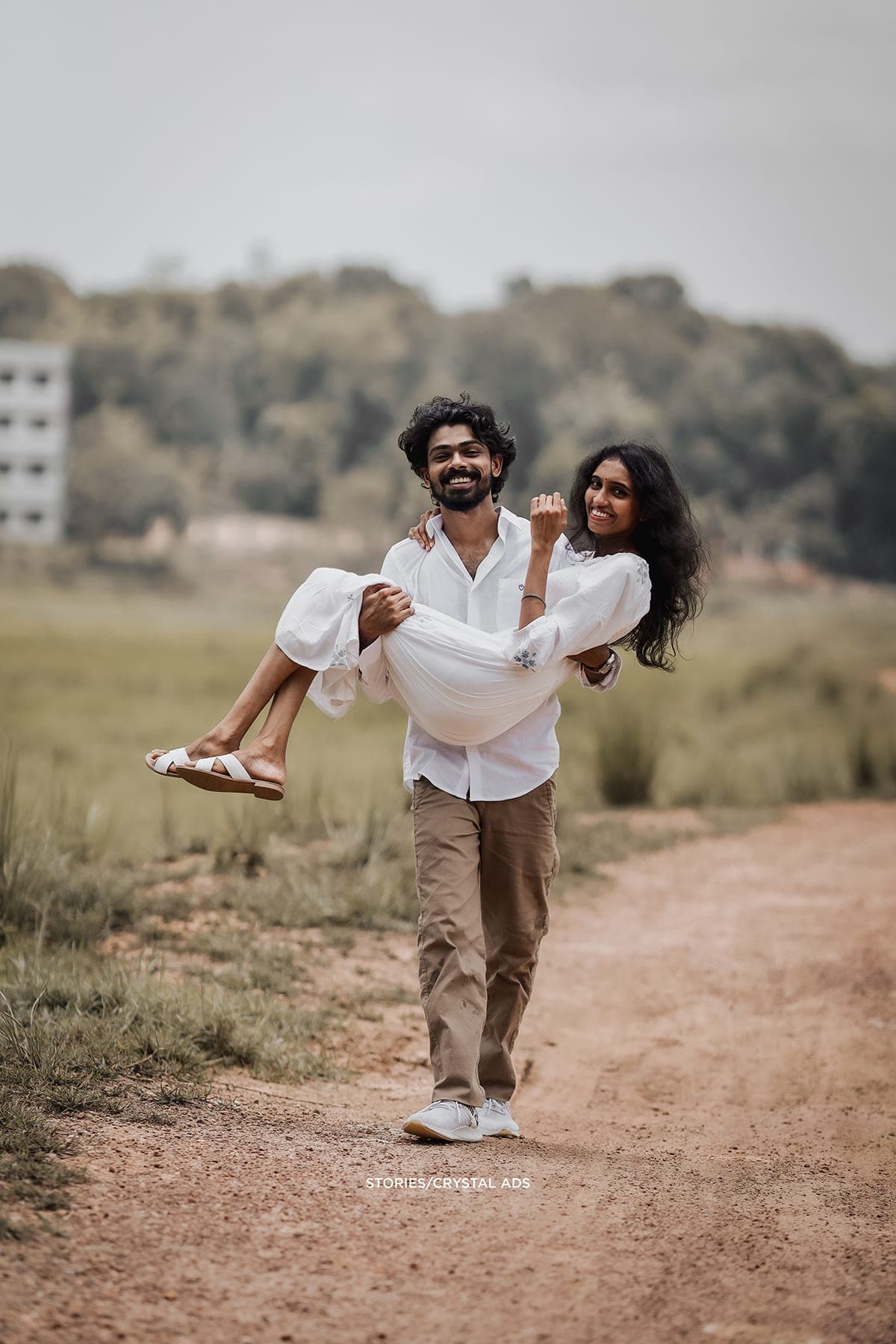 He carries her toward the camera, both laughing