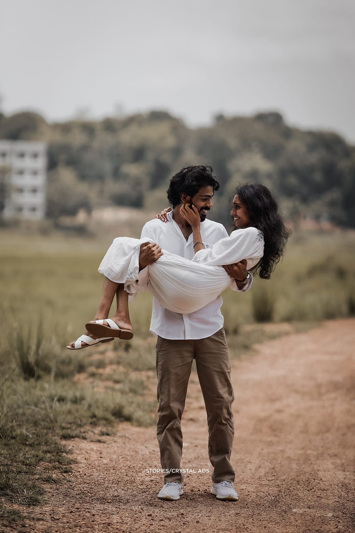 He carries her along the path, looking at her