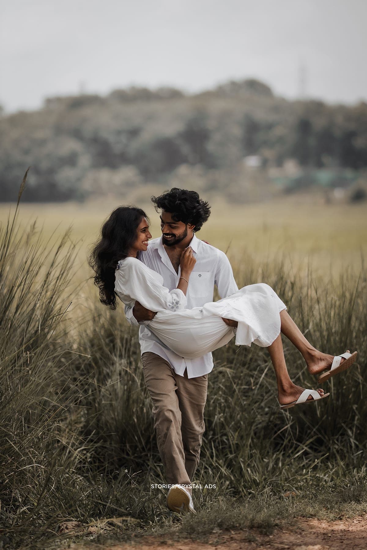 He holds her in his arms in the tall grass
