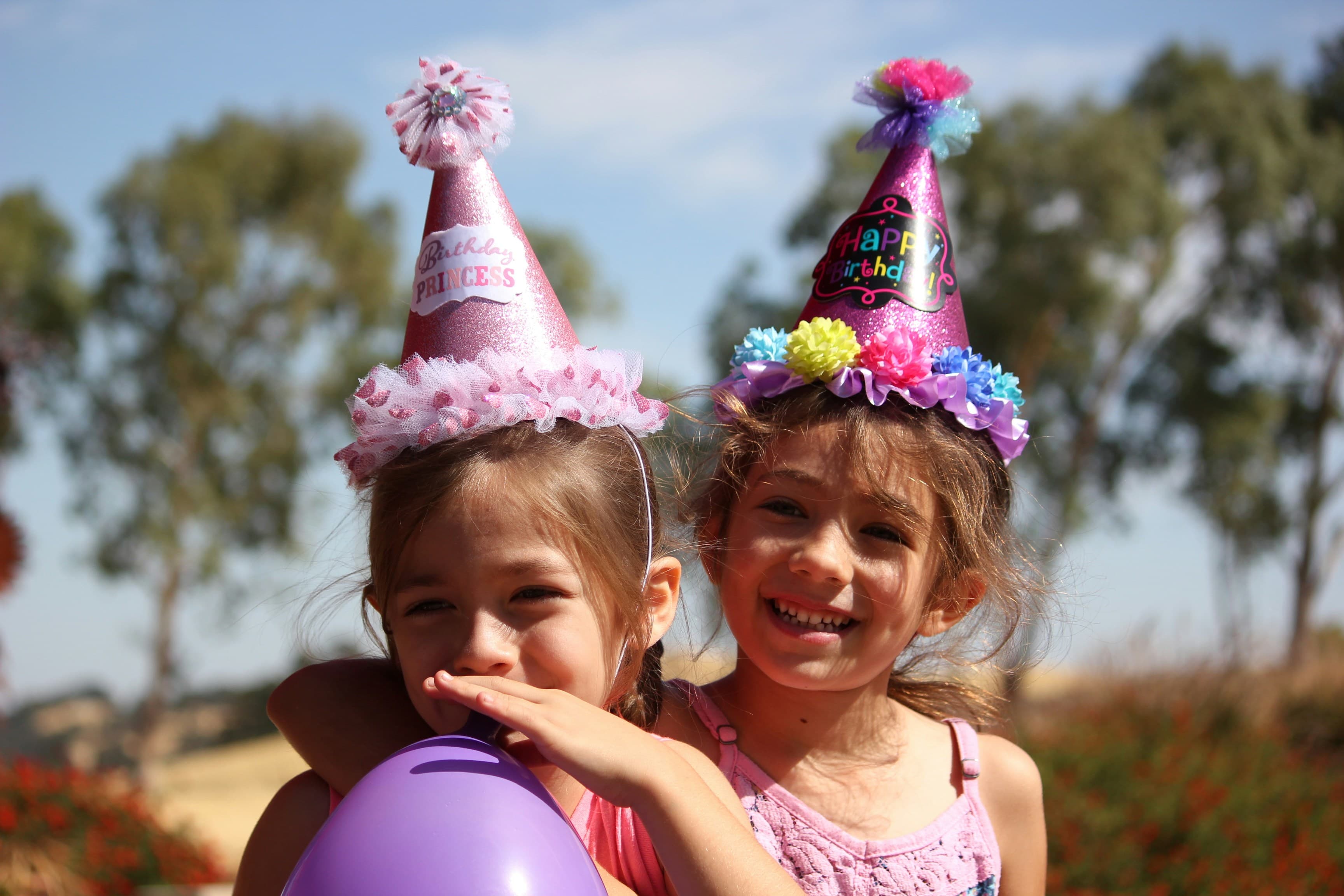 Two girls in birthday hats celebrating outdoors