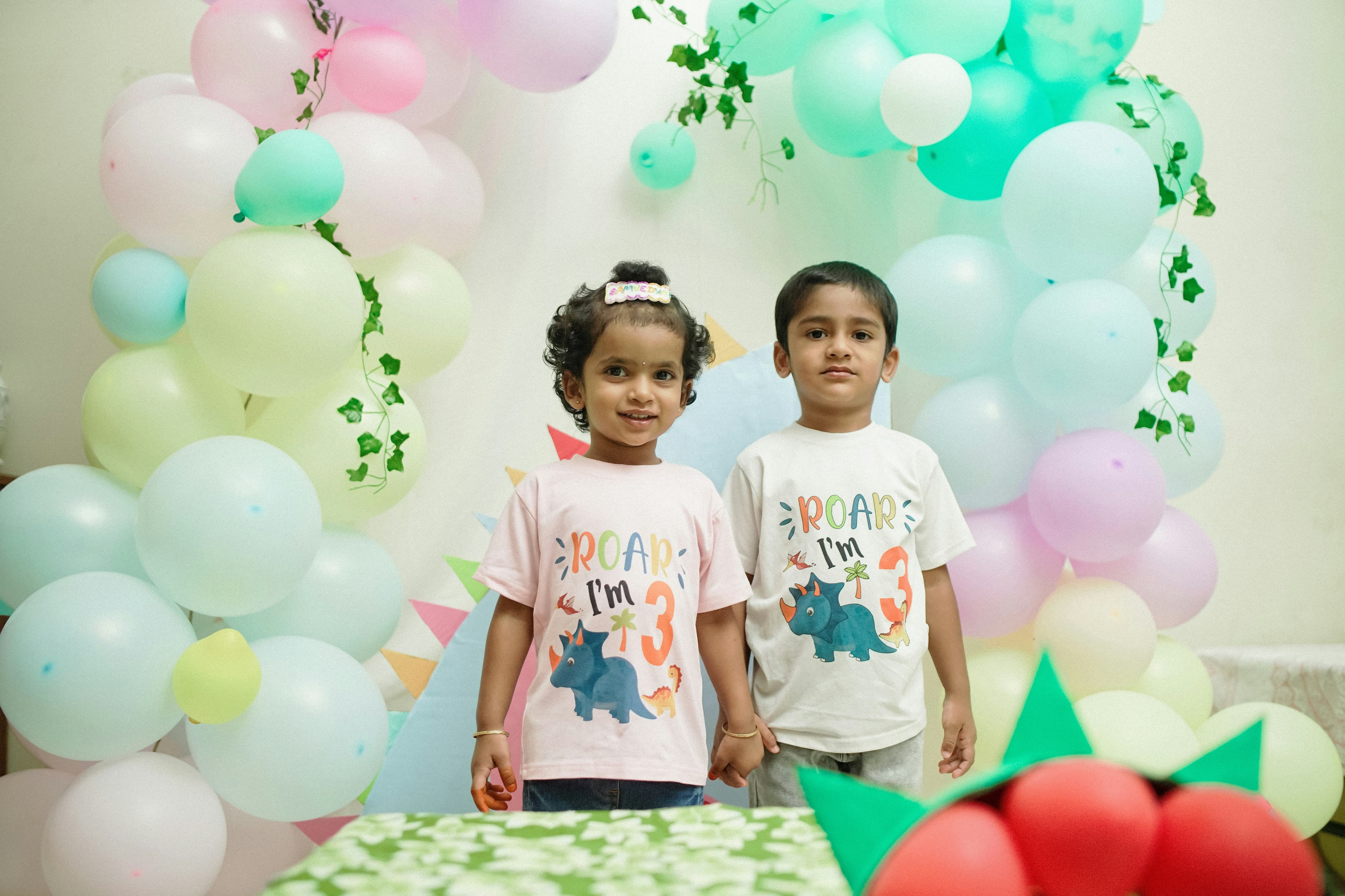 Two children standing by a balloon arch at a party
