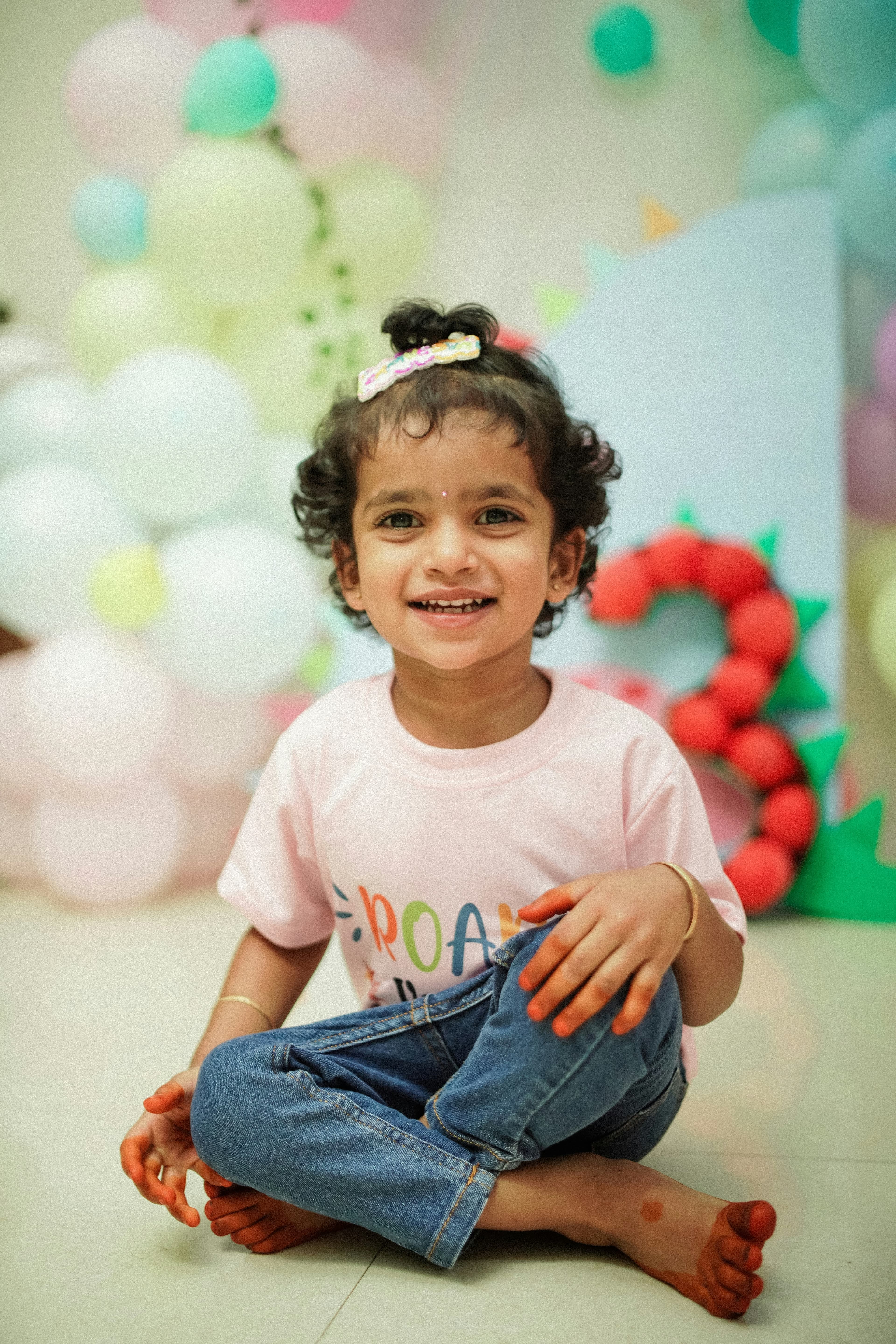 Smiling toddler sitting on the floor with balloons