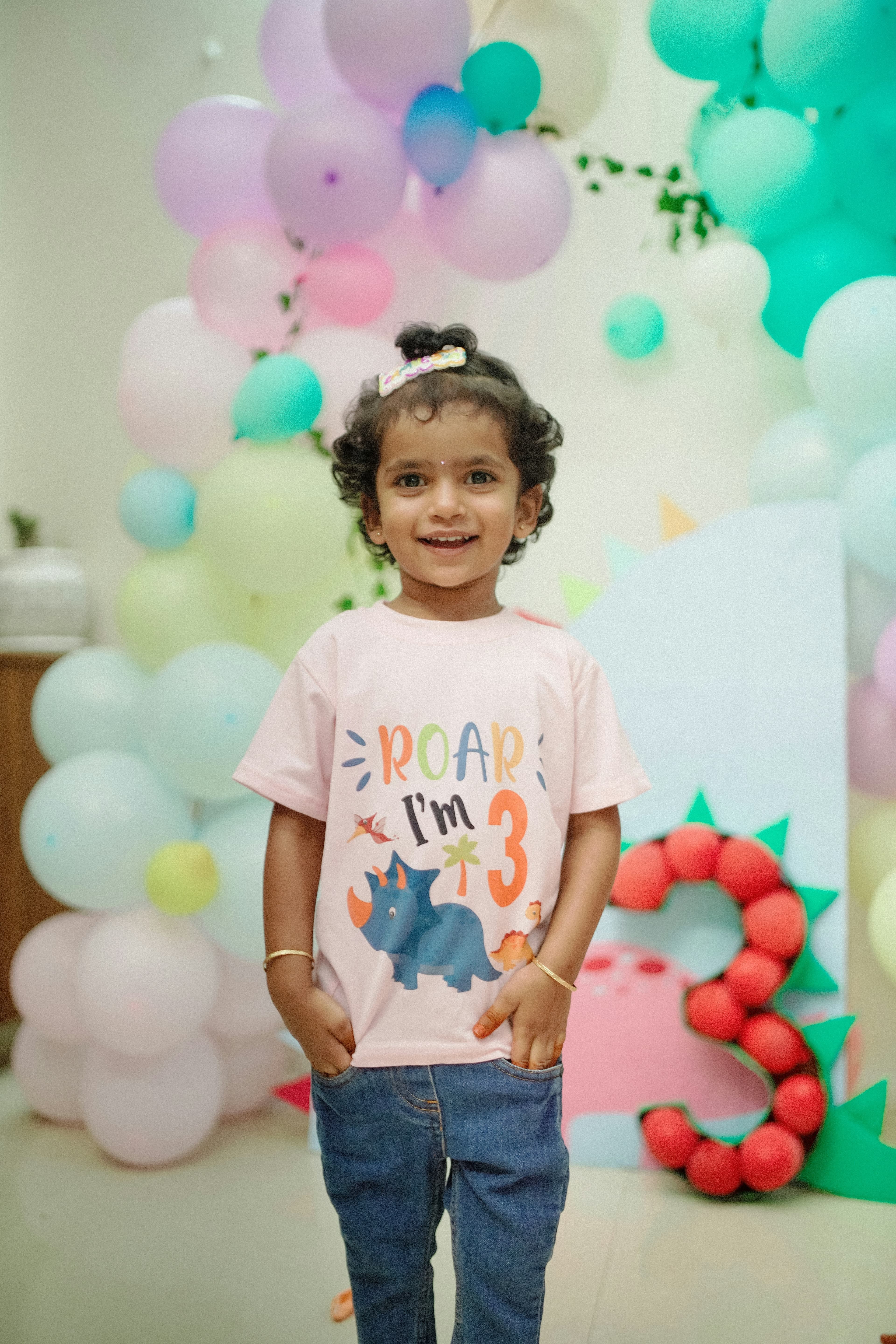 Smiling child in a dinosaur shirt with balloons